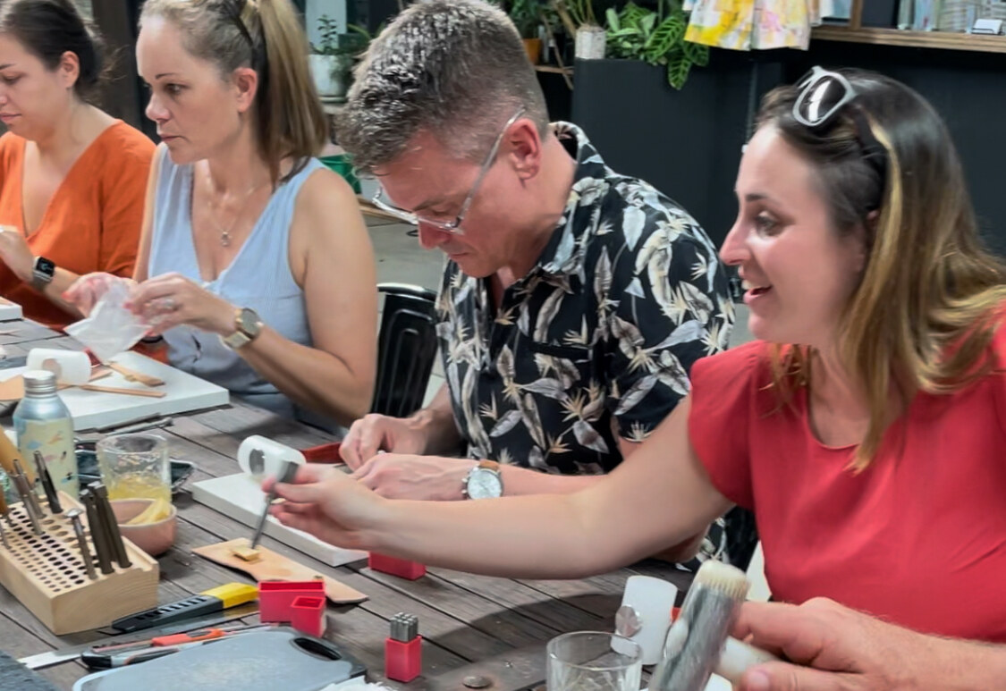 Four people laughing and stamping leather together at a leathercraft workshop in Murwillumbah