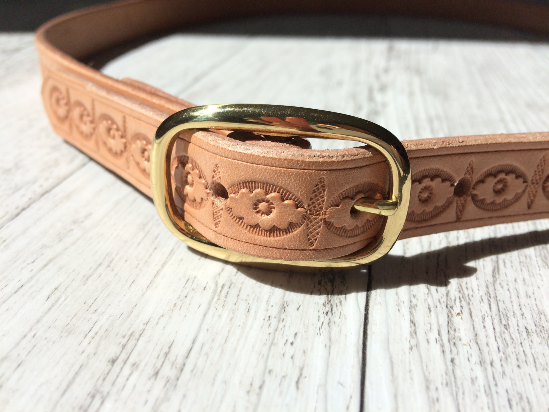 Stamping letters into a leather belt strap with a mallet at a belt making workshop